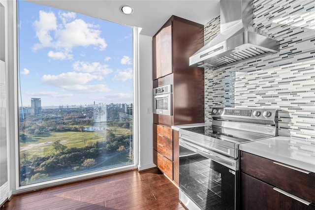 kitchen with stainless steel electric range, decorative backsplash, island range hood, and dark brown cabinetry