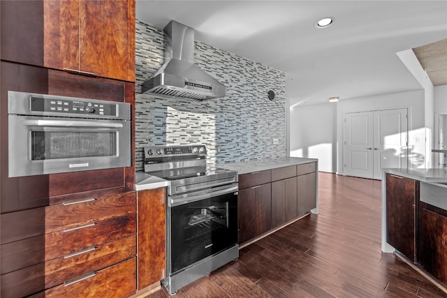 kitchen featuring dark hardwood / wood-style floors, stainless steel appliances, wall chimney exhaust hood, and backsplash