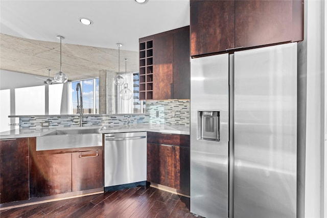 kitchen with appliances with stainless steel finishes, dark brown cabinetry, dark wood-type flooring, sink, and backsplash