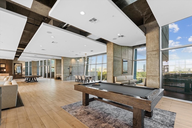 recreation room featuring floor to ceiling windows, a towering ceiling, and billiards