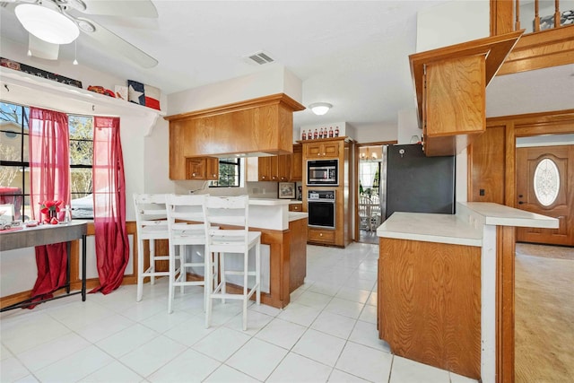 kitchen with a kitchen breakfast bar, plenty of natural light, kitchen peninsula, and black appliances