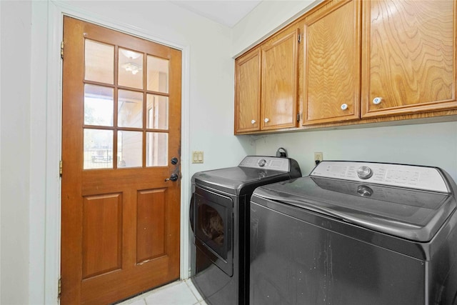 washroom featuring washing machine and dryer, cabinets, and light tile patterned floors