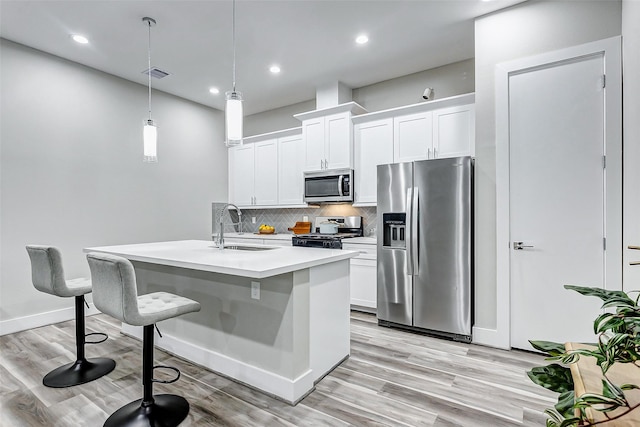 kitchen with white cabinetry, an island with sink, stainless steel appliances, decorative light fixtures, and sink