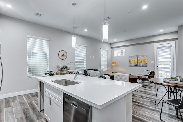 kitchen featuring white cabinets, dishwasher, decorative light fixtures, sink, and a center island with sink