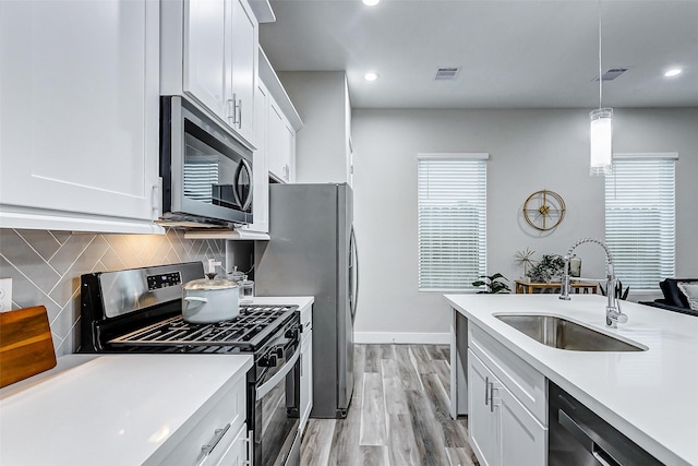 kitchen featuring white cabinetry, sink, pendant lighting, and stainless steel appliances