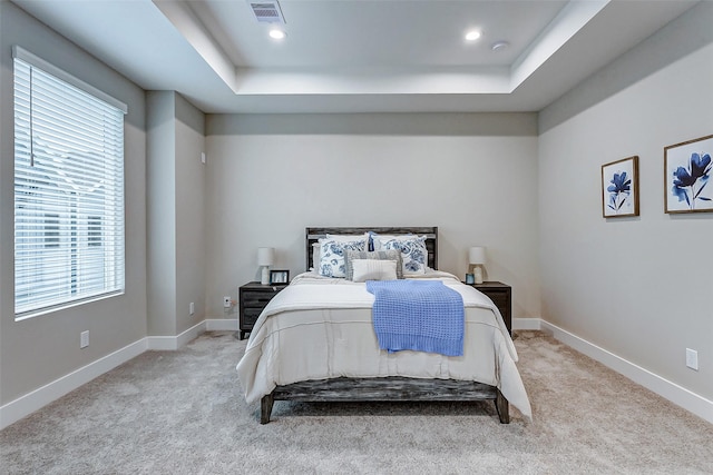 carpeted bedroom with a tray ceiling