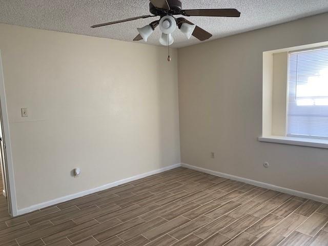 unfurnished room featuring ceiling fan, wood-type flooring, and a textured ceiling