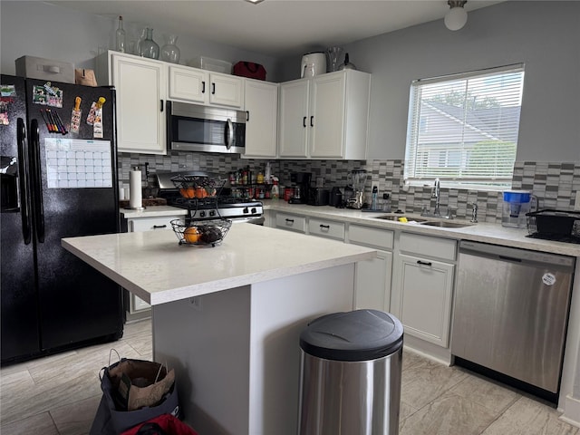 kitchen with white cabinetry, appliances with stainless steel finishes, decorative backsplash, sink, and a center island