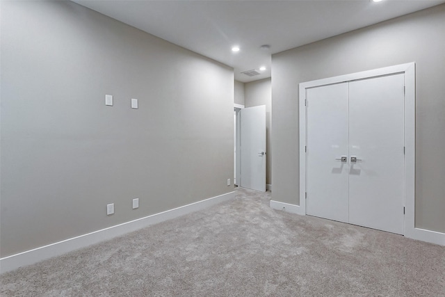 unfurnished bedroom with light colored carpet and a closet