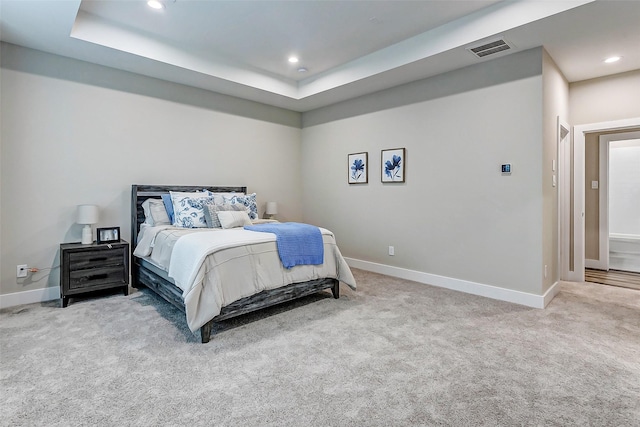 carpeted bedroom with a raised ceiling