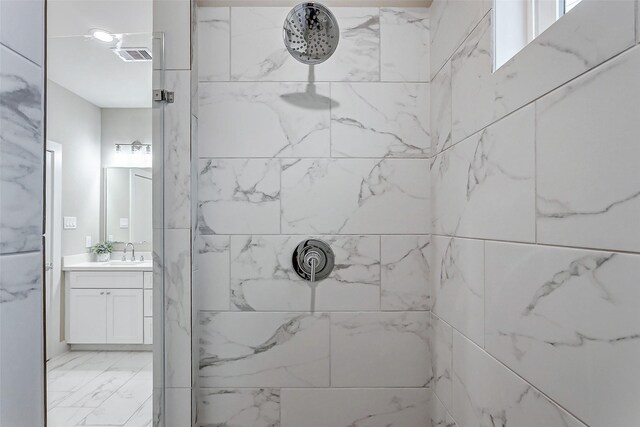 bathroom with a tile shower and vanity