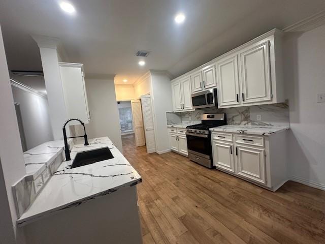 kitchen with light stone countertops, white cabinets, stainless steel appliances, tasteful backsplash, and sink