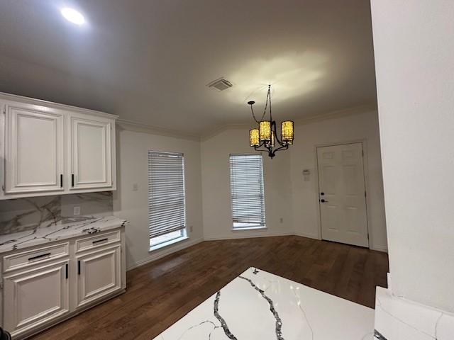 interior space featuring dark wood-type flooring, a chandelier, lofted ceiling, and ornamental molding