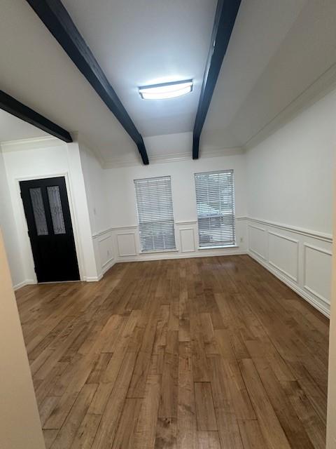 unfurnished room with hardwood / wood-style flooring and beam ceiling