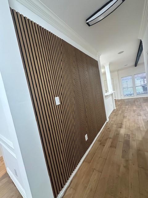 hallway with light wood-type flooring and ornamental molding