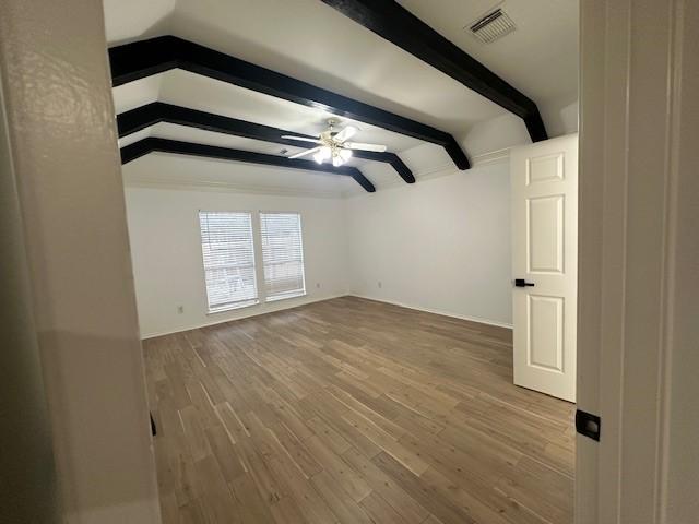 unfurnished room with ceiling fan, hardwood / wood-style floors, and vaulted ceiling with beams