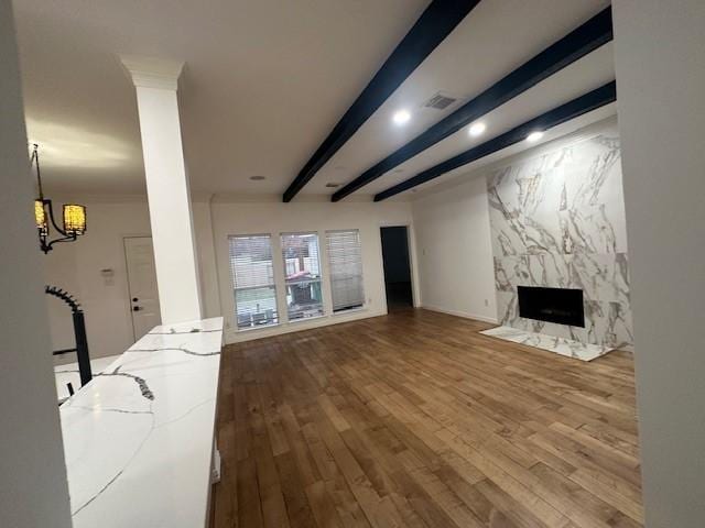 living room featuring wood-type flooring, a high end fireplace, and beam ceiling