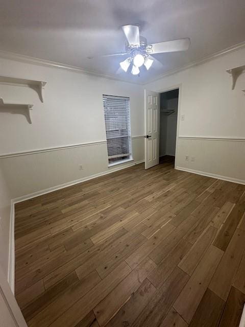 unfurnished bedroom featuring ceiling fan, a closet, dark hardwood / wood-style flooring, and crown molding