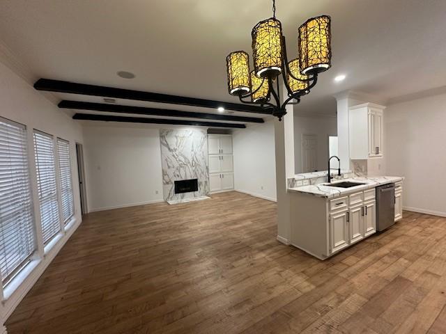 kitchen with light stone countertops, dishwasher, white cabinetry, sink, and beam ceiling