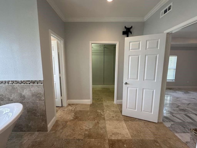 bathroom with tile walls, a bathing tub, and ornamental molding