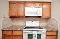 kitchen featuring light stone counters, white appliances, and tasteful backsplash