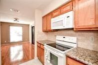 kitchen featuring backsplash, light stone counters, and white appliances