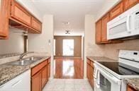 kitchen with light stone counters, sink, and white appliances