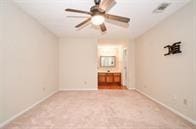 unfurnished bedroom featuring ceiling fan, light carpet, and ensuite bath