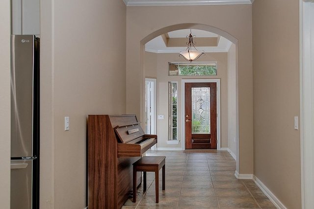 foyer with a raised ceiling and crown molding