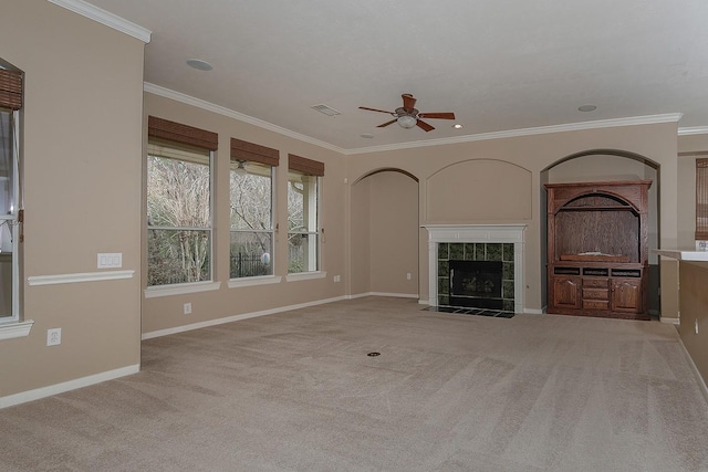 unfurnished living room featuring crown molding, a fireplace, light colored carpet, and ceiling fan