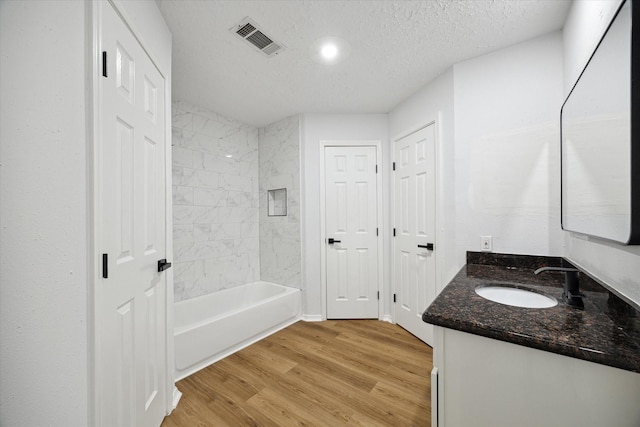 bathroom featuring vanity, tiled shower / bath combo, a textured ceiling, and hardwood / wood-style floors