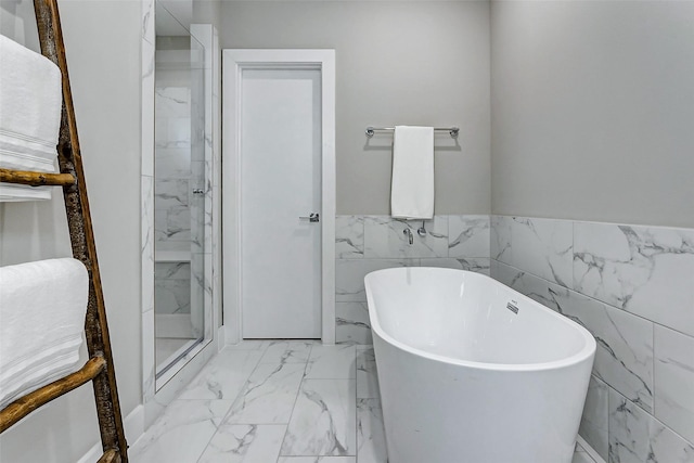 bathroom featuring shower with separate bathtub and tile walls