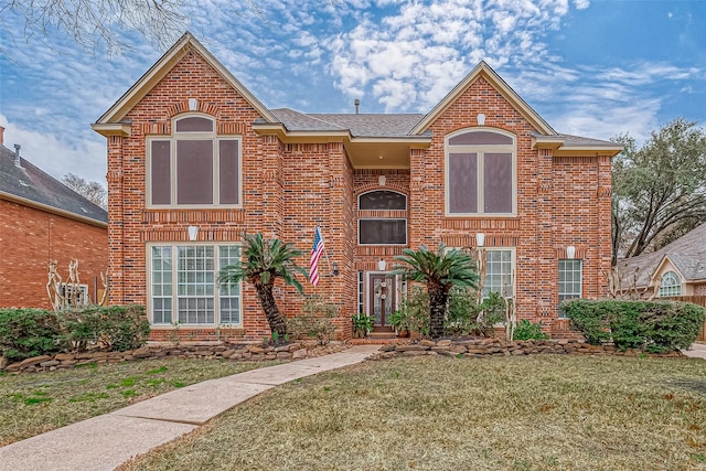 traditional-style house featuring a front yard and brick siding