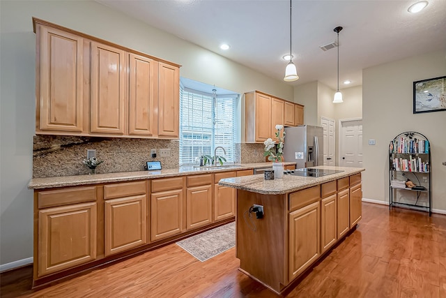 kitchen featuring tasteful backsplash, light wood-style flooring, black electric cooktop, stainless steel refrigerator with ice dispenser, and a sink