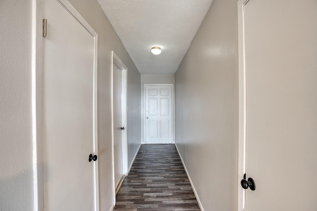 hallway with a textured ceiling and dark hardwood / wood-style flooring