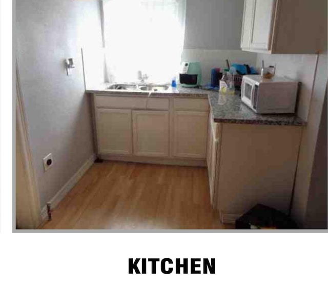 kitchen with sink, white cabinets, and light hardwood / wood-style flooring