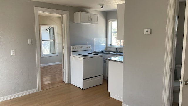 kitchen with white cabinetry, tasteful backsplash, white electric range, light hardwood / wood-style flooring, and sink