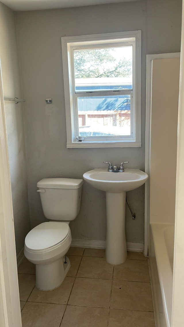 bathroom featuring sink, a washtub, tile patterned floors, and toilet