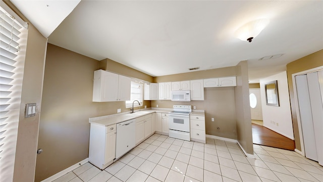 kitchen featuring sink, white appliances, white cabinetry, and light tile patterned flooring