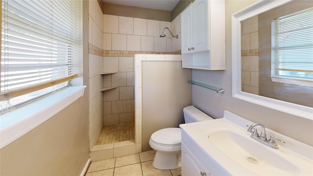 bathroom featuring toilet, vanity, a tile shower, and tile patterned flooring