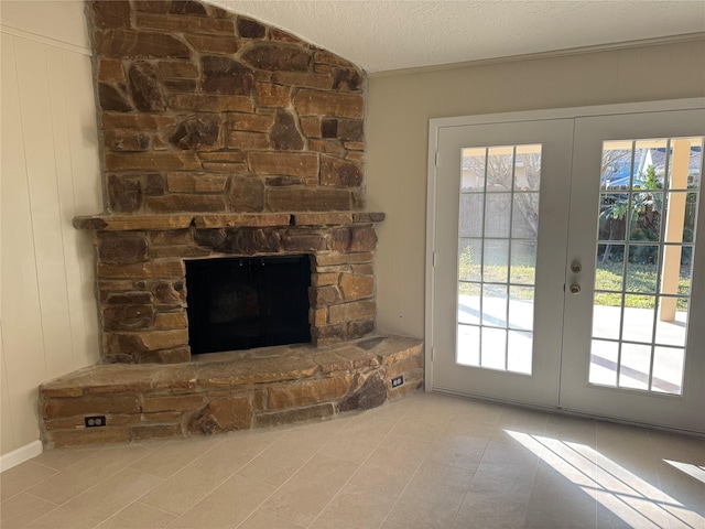 entryway featuring french doors, a fireplace, a textured ceiling, and vaulted ceiling