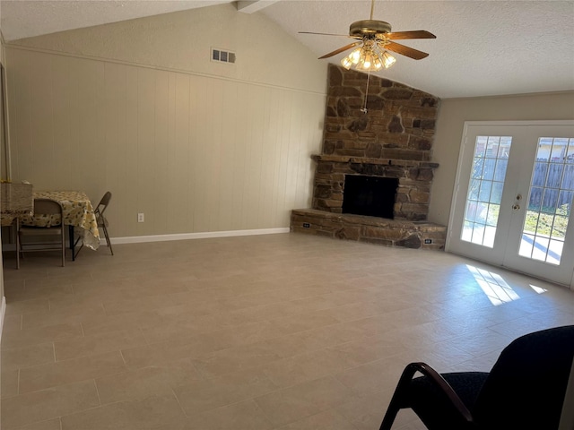 living room featuring ceiling fan, a fireplace, lofted ceiling with beams, a textured ceiling, and french doors