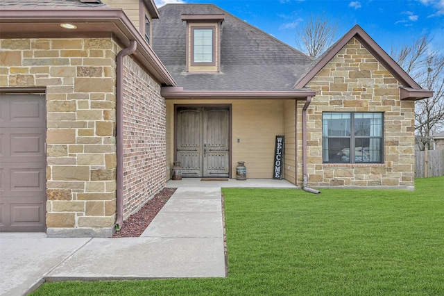 view of exterior entry with a garage and a lawn