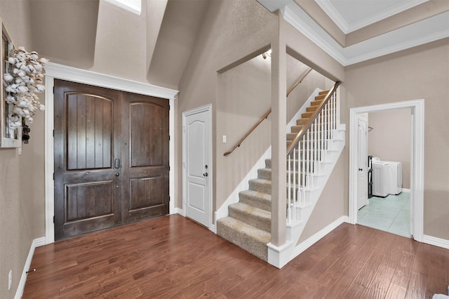 entrance foyer featuring washing machine and clothes dryer, ornamental molding, and hardwood / wood-style floors