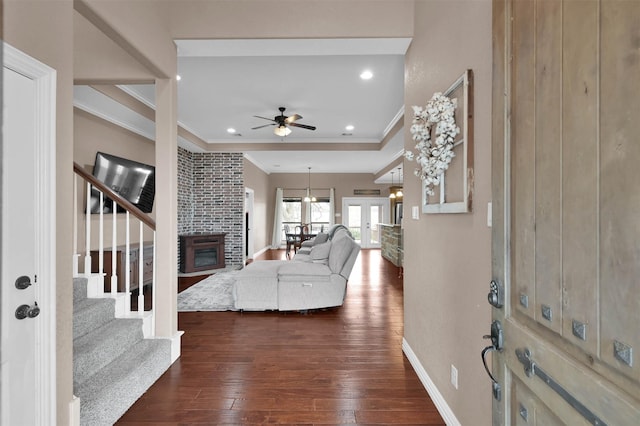 entryway with dark wood-type flooring, french doors, a fireplace, ceiling fan, and crown molding