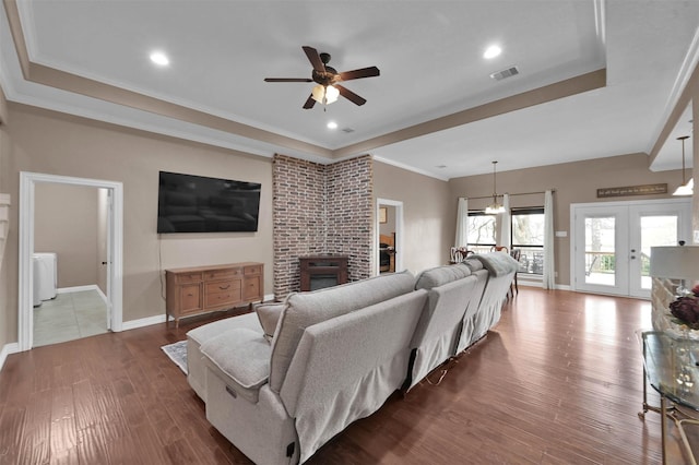 living room with french doors, a fireplace, hardwood / wood-style flooring, ornamental molding, and ceiling fan