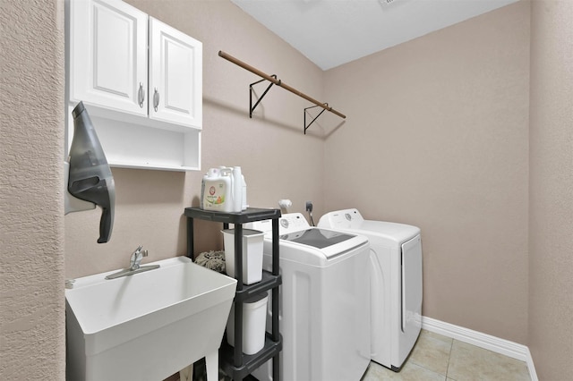 laundry room with cabinets, light tile patterned floors, washer and clothes dryer, and sink