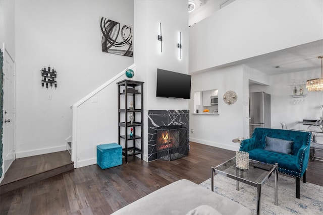 living room featuring a high end fireplace, a towering ceiling, and dark hardwood / wood-style floors