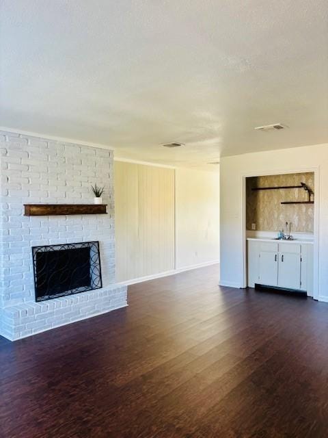 unfurnished living room with a brick fireplace and dark hardwood / wood-style floors