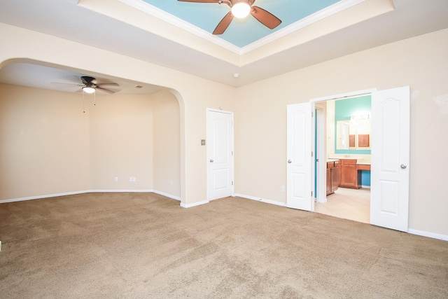 spare room featuring ceiling fan, a raised ceiling, and light colored carpet